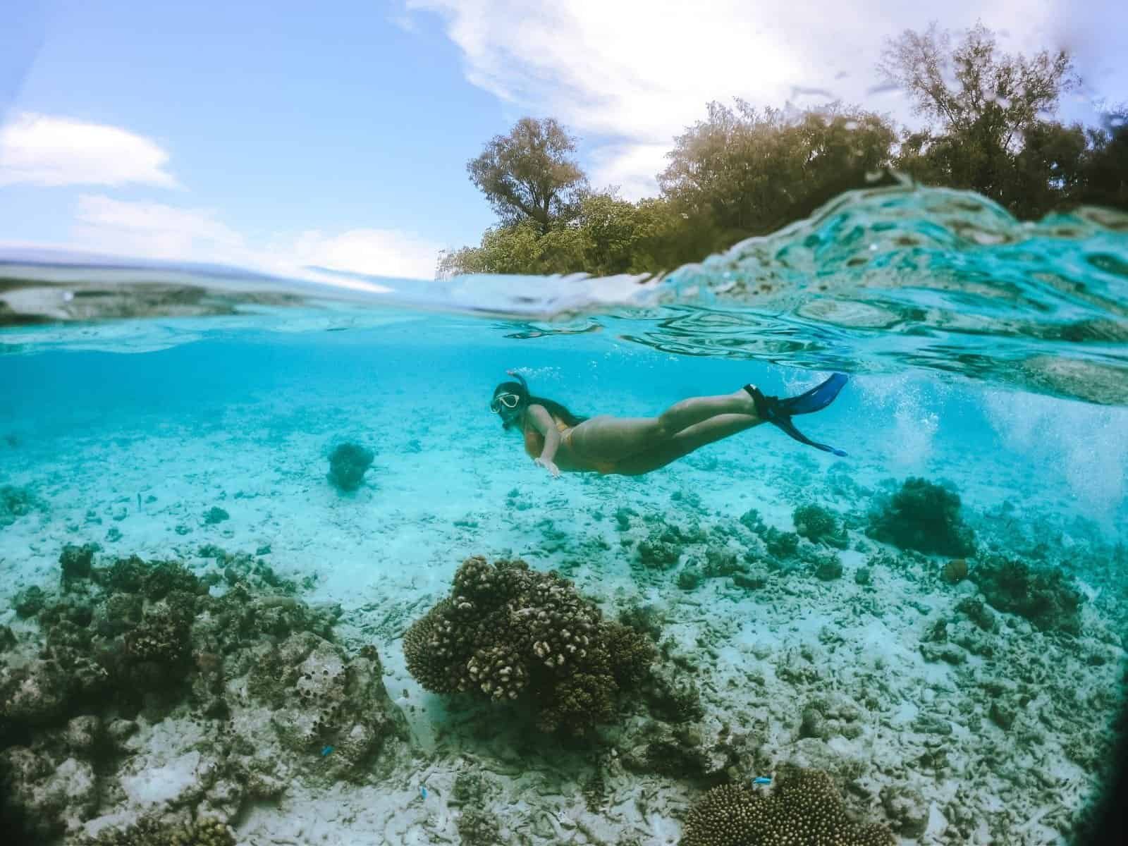 gopro dome underwater photo taken half underwear and half showing the island. Girl snorkelling in the solomon islands