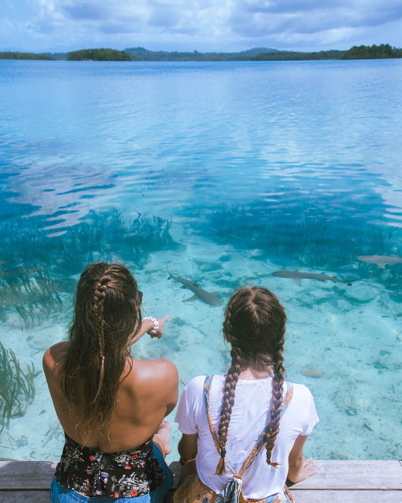 Zipolo Habu Resort - two girls watching reef sharks from the jetty. Things to do in the Solomon Islands
