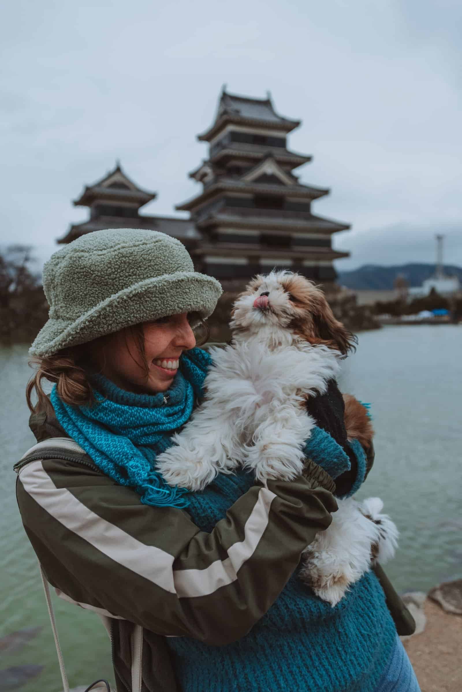 Girl cuddling cute fluffy dog infront of Matsumoto castle : Unique Things to Do in Japan
